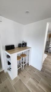 a white kitchen with a counter and stools in a room at 2 pièces d'environ 25m2 in Torcy