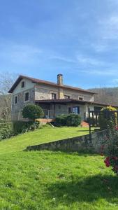 a house on a hill with a yard with green grass at Casa rural con piscina in Carasa
