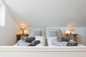 a white bed with two pillows on it with two lamps at Vályog Vendégház in Balatonendréd +25 photos