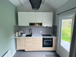 cocina con armarios blancos, fregadero y ventana en Blokhut Klein Meerzicht en Haren