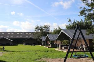 a group of huts in a field with a building at Camping De Kooiplaats in Schiermonnikoog