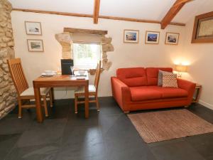 a living room with a red couch and a table at Godolphin Barn in Helston
