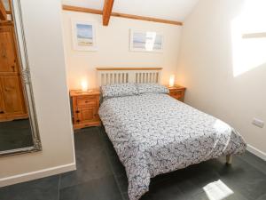 a bedroom with a bed and two night stands and a mirror at Godolphin Barn in Helston