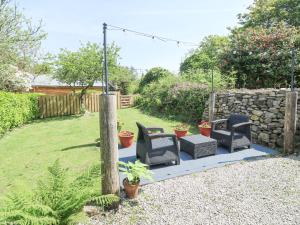 a garden with two chairs and a stone wall at Godolphin Barn in Helston