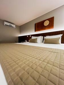 un grande letto in una stanza con un orologio a muro di Smart Hotel João Pessoa a João Pessoa