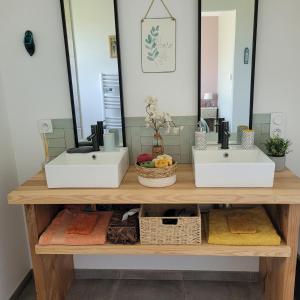 a bathroom counter with two sinks and a mirror at Pause 24 in Saint-Laurent-des-Vignes