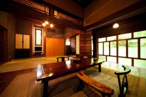 Großes Zimmer mit einem Holztisch und Stühlen. in der Unterkunft Hatago Kayausagi in Hita