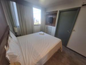 Hóspede já Nobile suites في برازيليا: غرفة نوم بسرير ابيض وتلفزيون
