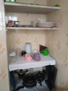 大普拉亚Kitnet Temporada Praia Grande SP - Completa com Wi-fi, garagem rotativa, 1 quadra da praia - no centro comercial Boqueirão的一个带碗碟、锅碗瓢盆的厨房架