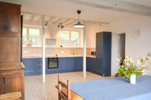 a large kitchen with blue cabinets and a table at Le Petit Luquis - maison de campagne 7 chambres - in Chézy-sur-Marne
