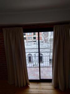 ein Fenster mit Vorhängen und Blick auf ein Gebäude in der Unterkunft Departamento Pleno Centro in San Salvador de Jujuy