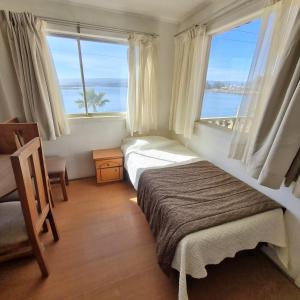 1 dormitorio con 2 camas y 2 ventanas grandes en Max & Mar Pichilemu en Pichilemu
