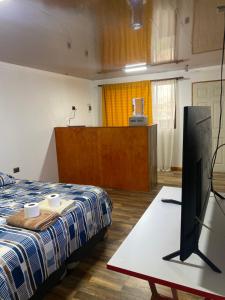 Habitación con cama y TV de pantalla plana. en Hostal Vicencio - Mini Departamentos, en Iquique