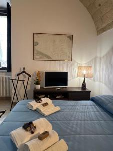 um quarto com uma cama com toalhas e uma televisão em Alle volte… em Bisceglie