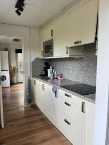 cocina con armarios blancos y encimera en Boshuis Luyksgestel 2-6 personen, veel privacy!, en Luyksgestel