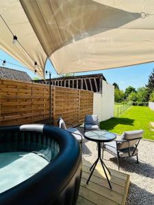 eine Terrasse mit einem Bett, einem Tisch und Stühlen in der Unterkunft La petite maison in Loeuilly