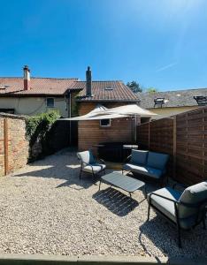 eine Terrasse mit Stühlen, einem Tisch und einem Sonnenschirm in der Unterkunft La petite maison in Loeuilly