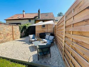 a patio with chairs and a table and a fence at La petite maison in Loeuilly