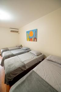 um quarto com quatro camas alinhadas contra uma parede em Pousada no coração de Londrina em Londrina