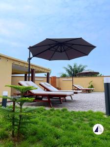a picnic table with a large umbrella and chairs at Residence P in Kribi