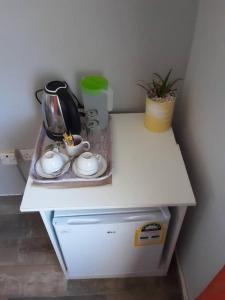a white counter with a tea kettle and cups on it at Homey Guesthouse in Gaborone