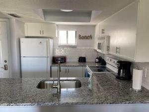 a kitchen with a sink and a white refrigerator at Ocean Side Ocean Village Condo in St. Augustine