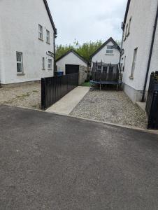 a driveway with two white houses and a fence at Ballinacross Lodge 