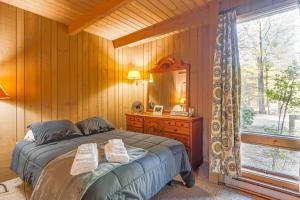 een slaapkamer met een bed, een spiegel en een raam bij All-Season Conway Condo with Private Hot Tub! in North Conway