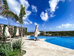 Una piscina de resort con una sombrilla y una persona. en Modern Studio Downtown with Rooftop, Pool, Gym and Parking, en Tulum