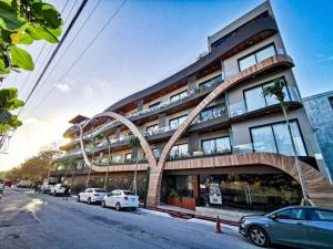 Un edificio con coches aparcados delante. en Modern Studio Downtown with Rooftop, Pool, Gym and Parking, en Tulum