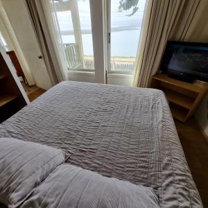 a bedroom with a bed and a television and a window at Max & Mar Pichilemu in Pichilemu