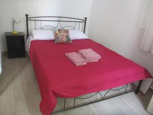 a bed with a red blanket and two towels at Karpasi House in Karpásion