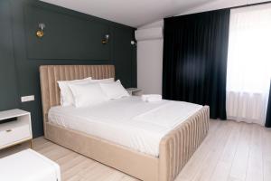 a bedroom with a large white bed with green walls at Villa Twins Techirghiol in Techirghiol