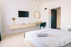 a white bedroom with a bed and a tv on the wall at Villa Twins Techirghiol in Techirghiol