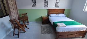 Amaca Suites في سانتا كروز دي لا سيرا: غرفة نوم بسرير وطاولة وكرسي