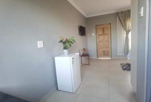 a room with a refrigerator with a vase of flowers on it at Monavy Riverside Hotels in Tzaneen in Lenyenye