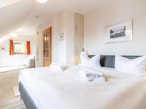 - une chambre blanche avec un grand lit blanc et des oreillers blancs dans l'établissement Dünenhof DÜNENHOF Whg. D-11, à Wustrow