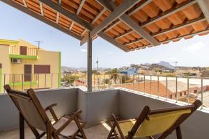 2 Stühle auf einem Balkon mit Stadtblick in der Unterkunft Maya Apartments in Mindelo