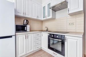 uma cozinha com armários brancos e um forno preto em Однокомнатные апартаменты на Мангилик ел 51 em Astana