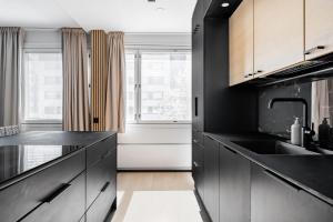 a black kitchen with a sink and a window at Lux Eight, 2-Bedroom City Centrum in Turku +11 photos