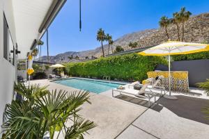 a pool with chairs and an umbrella next to a house at *Condo - 606 W Arenas Rd Unit 3, Palm Springs in Palm Springs