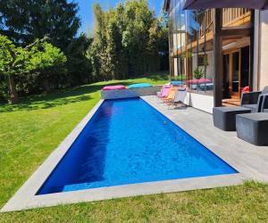 a swimming pool in the backyard of a house at VILLA "Le Jardin" 4 étoiles - Piscine chauffée couloir 12m - Spa Balnéo Hammam - 4 Chambres dont une Love Room de 35m2 avec lit rond, vidéo projecteur Netflix, climatisation in Jardin