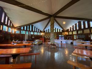 Habitación grande con mesas y bancos de madera. en Centro Turístico Anticura Parque Nacional Puyehue, 