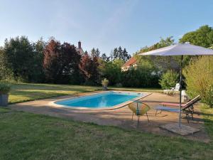 Varennes-lès-Narcy的住宿－Le Domaine du Château，游泳池配有遮阳伞、椅子、桌子和遮阳伞