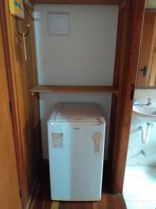 a small white refrigerator in a bathroom next to a sink at Pousada da Praia II in Guarujá