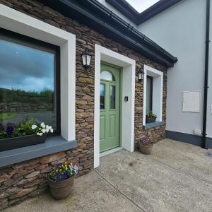 una casa de ladrillo con una puerta verde y ventanas en The Cé Hideout, en Tralee