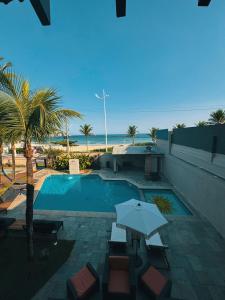 a pool with chairs and an umbrella next to the beach at Luna Hotel Boutique - Beira Mar in Guarujá