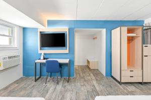 a room with a desk and a tv on a blue wall at Tropicana Motel Wildwood Beach & Boardwalk in Wildwood