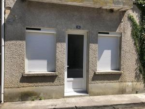 two windows with white blinds on the side of a building at Appartement lumineux tout équipé in Caussens