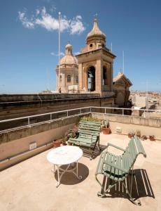 eine Gruppe Stühle und ein Tisch auf einem Gebäude in der Unterkunft Birgu No 25 apartment 3 in Vittoriosa